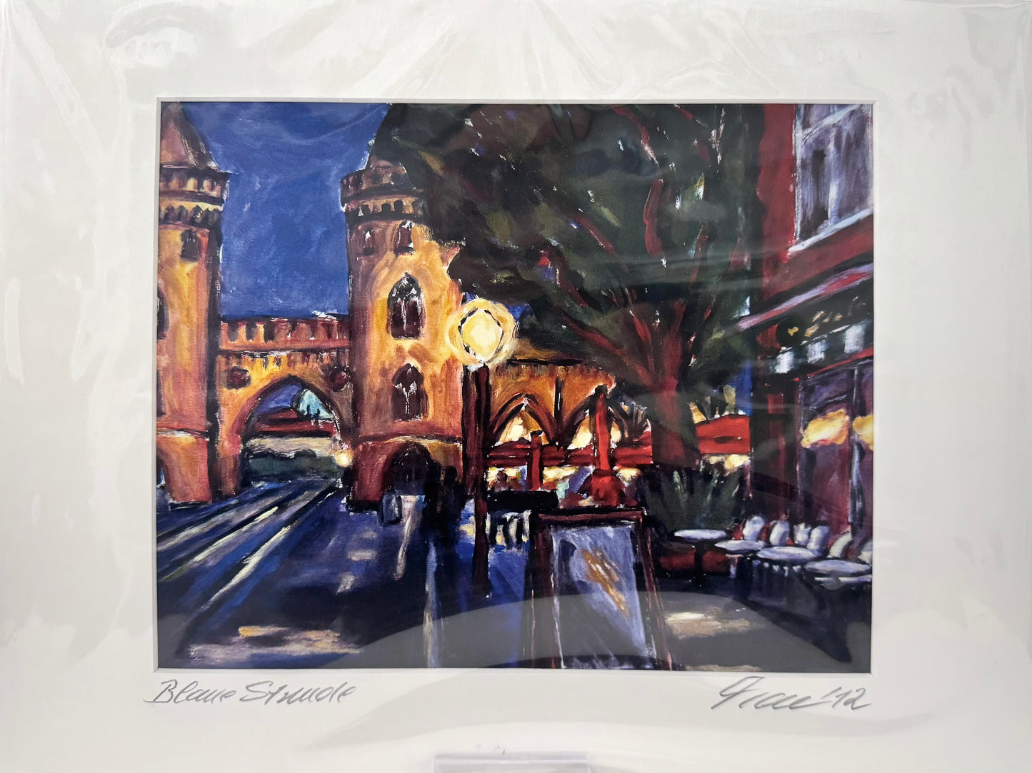 Druck, handsigniert von Ute Manoloudakis, Titel „Blaue Stunde“ – impressionistischer Blick zum Nauener Tor, Abendstimmung, Straßenlaterne, ein Baum, Cafeszenerie. Potsdam, historische Architektur. Im Passepartout - erhältlich bei What The Artist Made