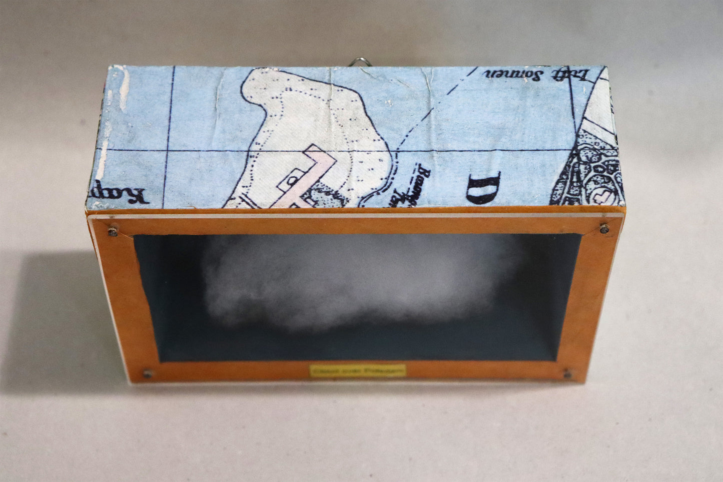Original Objekt - Assemblage von Elisabeth Dishur, Titel „Clouds over Potsdam"– Objektkiste. Draufsicht auf Stadtkarte auf der Holzkiste: Papiercollage mit Stadtkarte von Potsdam umfassend auf der Kiste.  Objektcollage, erhältlich bei Galerie Waldbach - What The Artist Made