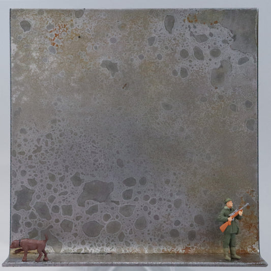 Original Objekt - Assemblage von Katrin Schramm, Titel „Jagd ohne Hund ist...“ – Metallwinkel mit Miniatur-Figuren: Ein Jäger steht am rechten Rand des Winkels und schaut aus dem Werk heraus. Ein Hund steht am linken Rand und zeigt an. Er schaut in die andere Richtung. Dahinter das Metall des Winkels mit Struktur, als Hintergrund. Objektcollage, erhältlich bei Galerie Waldbach - What The Artist Made