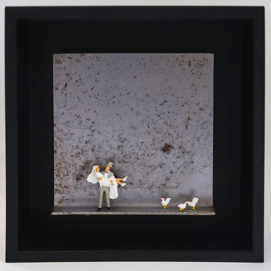 Original Objekt - Assemblage von Katrin Schramm, Titel „Dem Himmel so nah...“ – Metallwinkel mit Miniatur-Figuren: Ein Brautpaar, der Bräutigam trägt die Braut in den Armen. Rechts neben ihnen stehen drei weiße Hühner. Dahinter das Metall des Winkels mit Struktur, als Hintergrund. Objektcollage im schwarzen Rahmen, erhältlich bei Galerie Waldbach - What The Artist Made