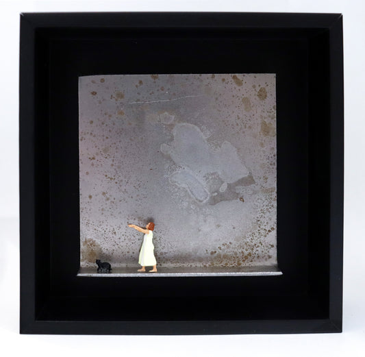 Original Objekt - Assemblage von Katrin Schramm, Titel „Ein schmaler Grat.“ – Metallwinkel mit Miniatur-Figuren: Eine Frau im Nachthemd läuft schlafwandelnd, die Arme ausgestreckt, auf den linken Rand zu.  Vor ihr läuft eine schwarze Katze in die gleiche Richtung. Dahinter das Metall des Winkels mit Struktur, als Hintergrund. Objektcollage im schwarzen Rahmen, erhältlich bei Galerie Waldbach - What The Artist Made