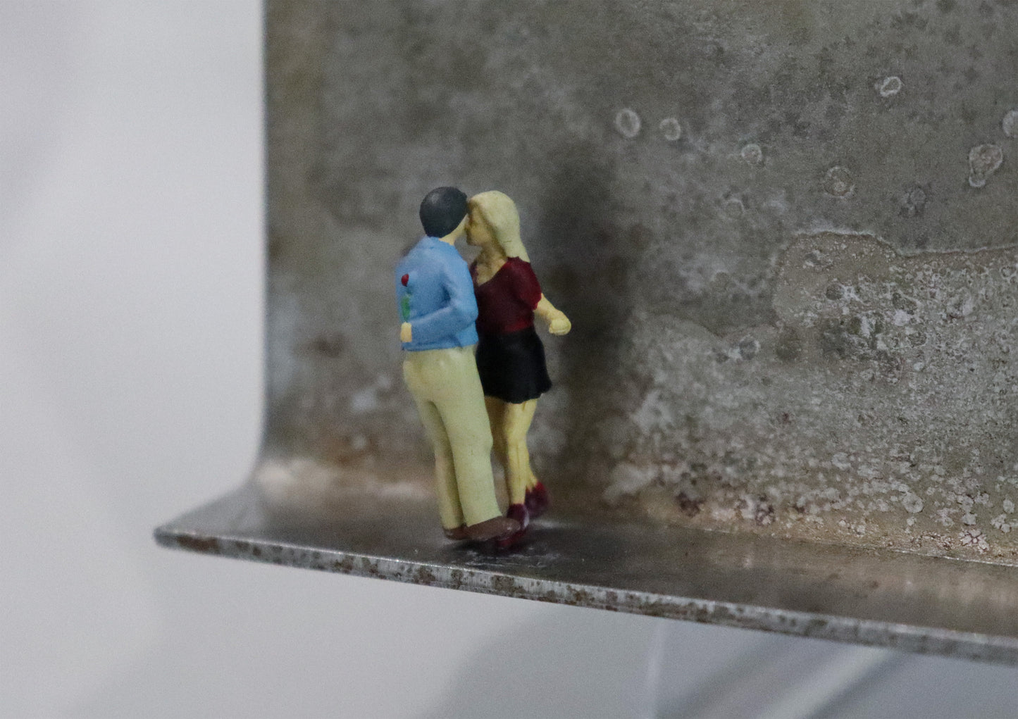 Original Objekt - Assemblage von Katrin Schramm, Titel „Endlich!“  – Metallwinkel mit Miniatur-Figuren, Detailansicht. Objektcollage, erhältlich bei Galerie Waldbach - What The Artist Made