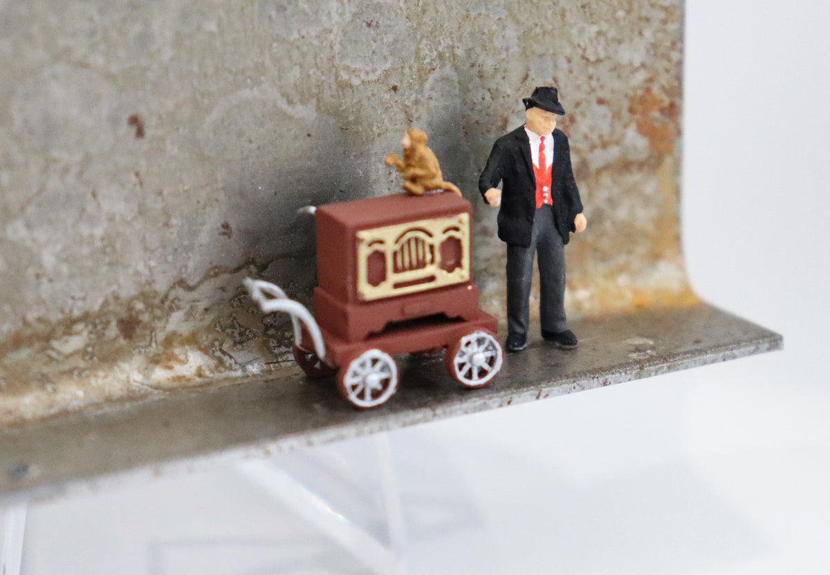Original Objekt - Assemblage von Katrin Schramm, Titel „Gib dem Affen Zucker...“ – Metallwinkel mit Miniatur-Figuren, Detailansicht. Objektcollage, erhältlich bei Galerie Waldbach - What The Artist Made