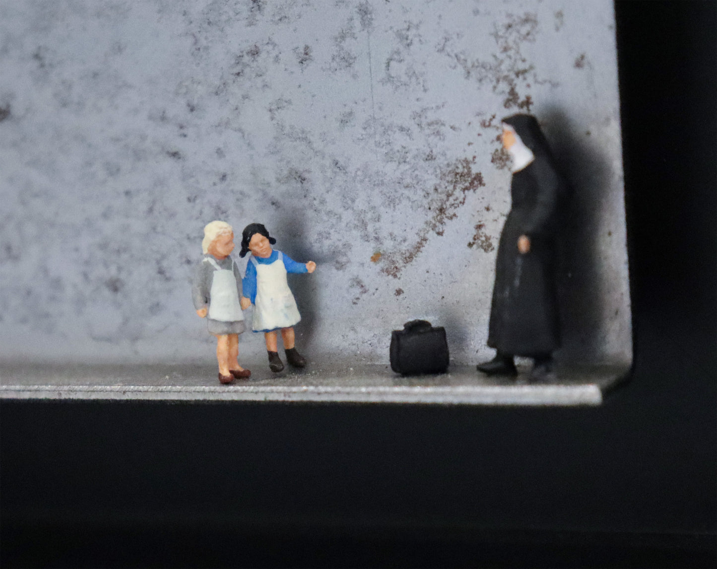 Original Objekt - Assemblage von Katrin Schramm, Titel „Jedes Kind ist kostbar.“ – Metallwinkel mit Miniatur-Figuren, Detailansicht. Objektcollage im schwarzen Rahmen, erhältlich bei Galerie Waldbach - What The Artist Made