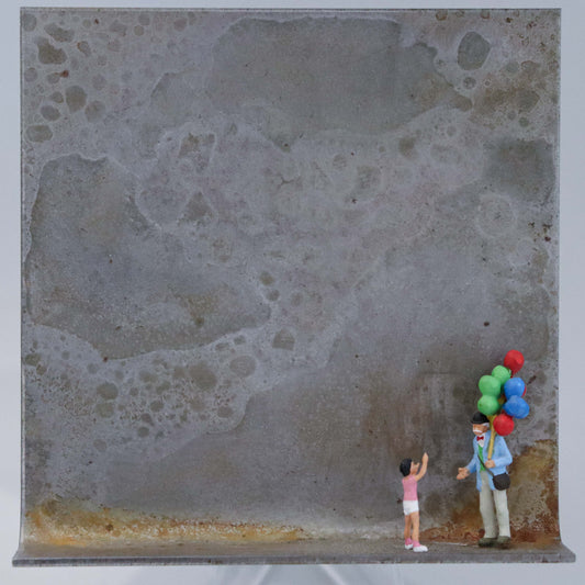 Original Objekt - Assemblage von Katrin Schramm, Titel „Lass sie fliegen!“  – Metallwinkel mit Miniatur-Figuren: Ein Kind zeigt auf die Luftballons eines Luftballonverkäufers mit vielen Ballons. Beide stehen am rechten Rand des Winkels. Dahinter das Metall des Winkels mit Struktur, als Hintergrund. Objektcollage, erhältlich bei Galerie Waldbach - What The Artist Made