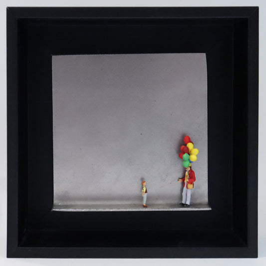 Original Objekt - Assemblage von Katrin Schramm, Titel „Lass sie fliegen...“ – Metallwinkel mit Miniatur-Figuren: Ein Ballonverkäufer steht auf der rechten Seite des Winkels und hält ein Bündel Ballons in der Hand. Vor ihm steht ein Kind und schaut  zu ihm und den Ballons hoch. Dahinter das Metall des Winkels mit Struktur, als Hintergrund. Objektcollage im schwarzen Rahmen, erhältlich bei Galerie Waldbach - What The Artist Made