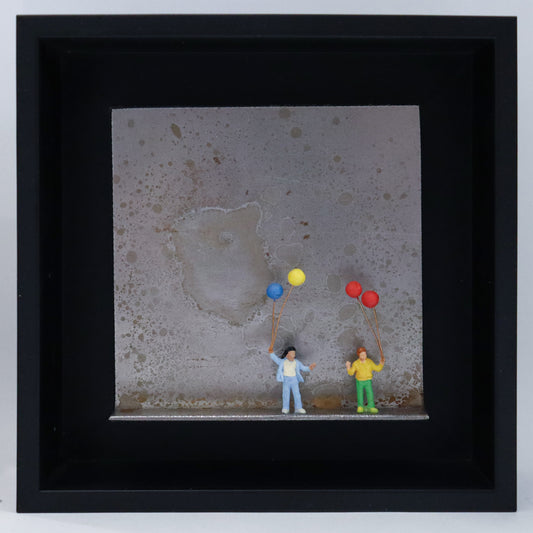 Original Objekt - Assemblage von Katrin Schramm, Titel „Mehr als nur Luft...“ – Metallwinkel mit Miniatur-Figuren: Zwei Kinder stehen auf dem Boden des Winkels und halten jeweils zwei Luftballons in der Hand. Dahinter das Metall des Winkels mit Struktur, als Hintergrund. Objektcollage im schwarzen Rahmen, erhältlich bei Galerie Waldbach - What The Artist Made
