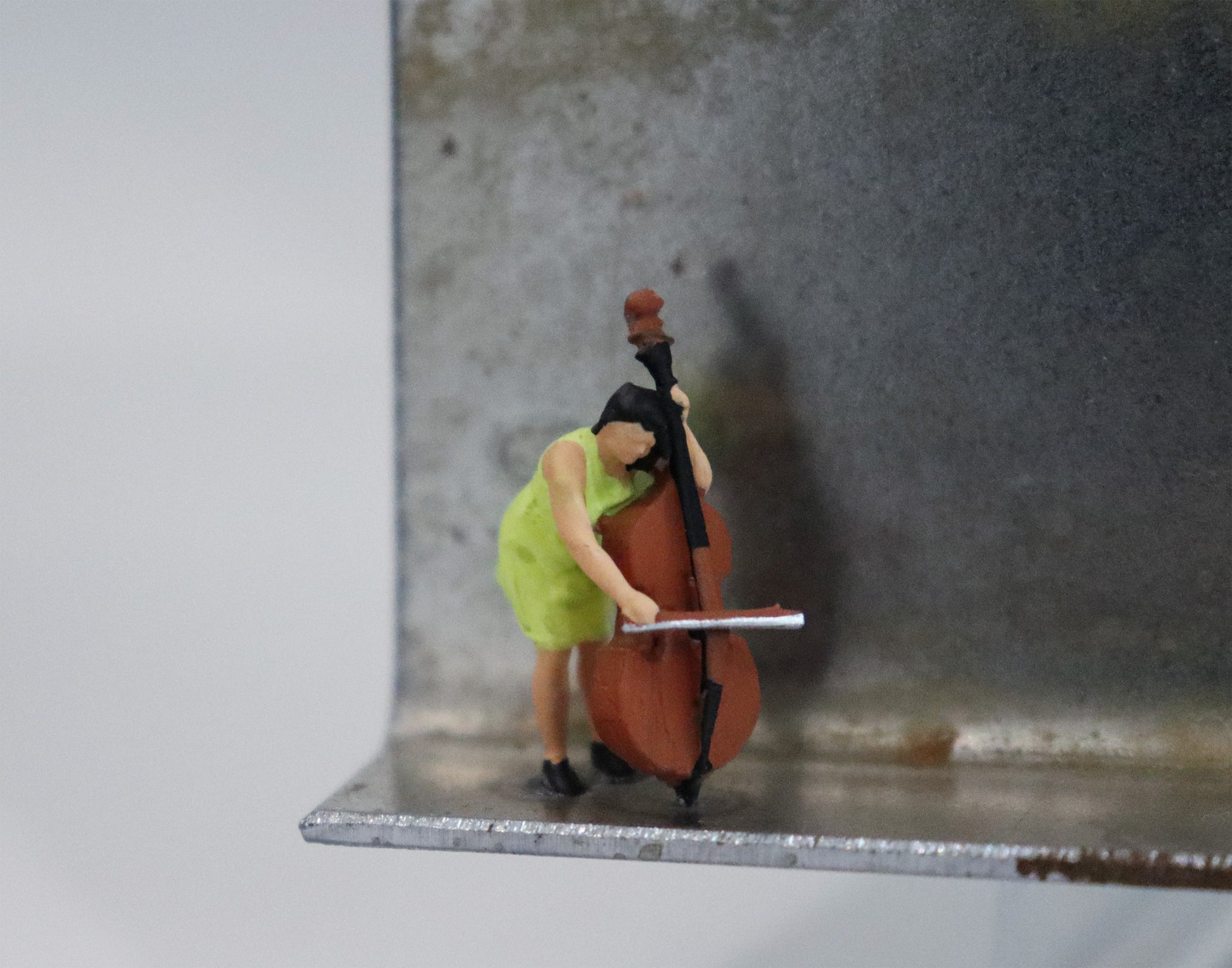 Original Objekt - Assemblage von Katrin Schramm, Titel „Schwer zu tragen. leicht zu  lieben.“  – Metallwinkel mit Miniatur-Figur, Detailansicht. Objektcollage, erhältlich bei Galerie Waldbach - What The Artist Made