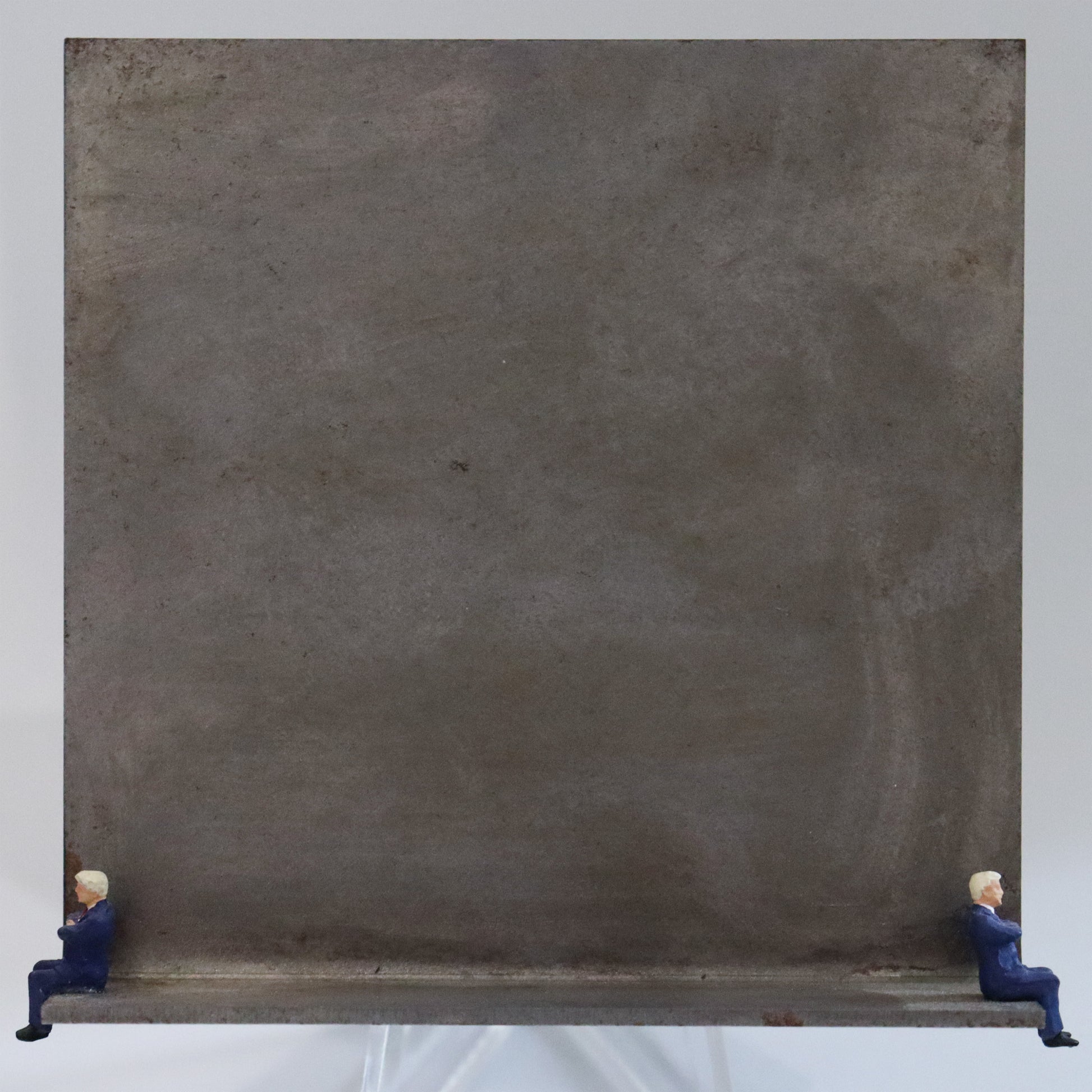 Original Objekt - Assemblage von Katrin Schramm, Titel „Warten auf Godot.“  – Metallwinkel mit Miniatur-Figuren: Zwei Männer in Anzügen sitzen mit verschränkten Armen jeweils am Rand des Winkels und schauen in die Ferne. Dahinter das Metall des Winkels mit Struktur, als Hintergrund. Objektcollage, erhältlich bei Galerie Waldbach - What The Artist Made