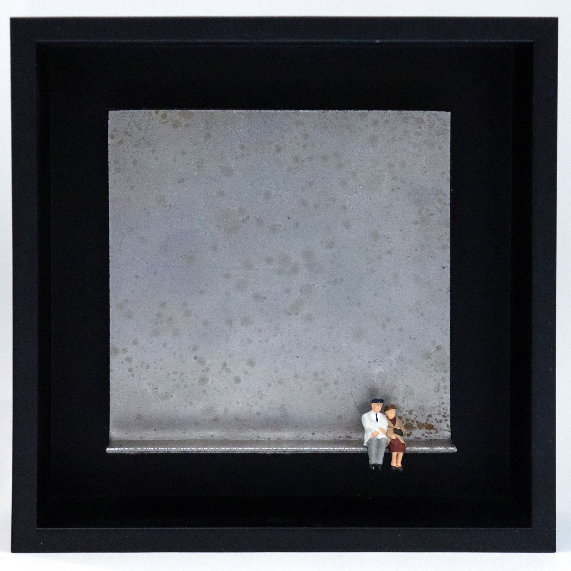 Original Objekt - Assemblage von Katrin Schramm, Titel „Wolke 9“ – Metallwinkel mit Miniatur-Figuren: Ein altes Paar sitzt am rechten Rand des Winkels und schaut in die Ferne. Dahinter das Metall des Winkels mit Struktur, als Hintergrund. Objektcollage im schwarzen Rahmen, erhältlich bei Galerie Waldbach - What The Artist Made