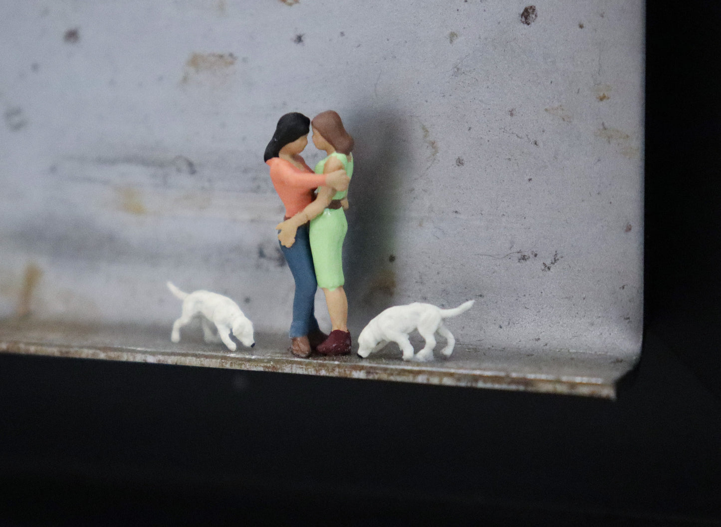 Original Objekt - Assemblage von Katrin Schramm, Titel „Bonding.“ – Metallwinkel mit Miniatur-Figuren, Detailansicht. Objektcollage im schwarzen Rahmen, erhältlich bei Galerie Waldbach - What The Artist Made
