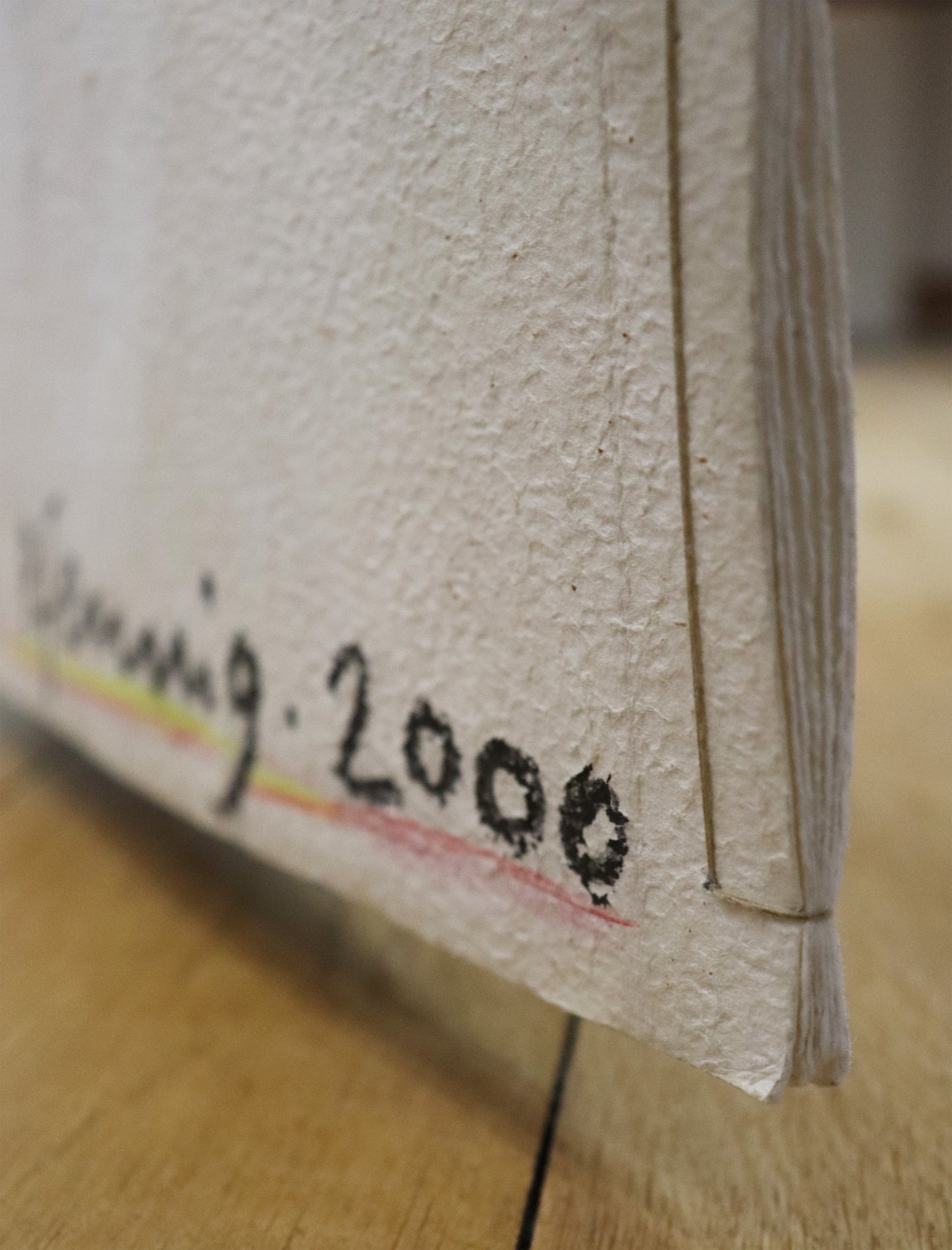 Original Mixed-Media-Objekt von Wolf-Dieter-Pfennig, Titel „Im Atemholen“  – gestaltetes Buch/Heft mit Illustrationen und Textstellen aus Goethes „Westöstlicher Divan - Buch des Sängers“. Detailansicht der Signatur W.-D. Pfennig 2000 und der Bindung der Papiere. Mixed Media auf Papier, signiert, erhältlich bei Galerie Waldbach, What the Artist Made